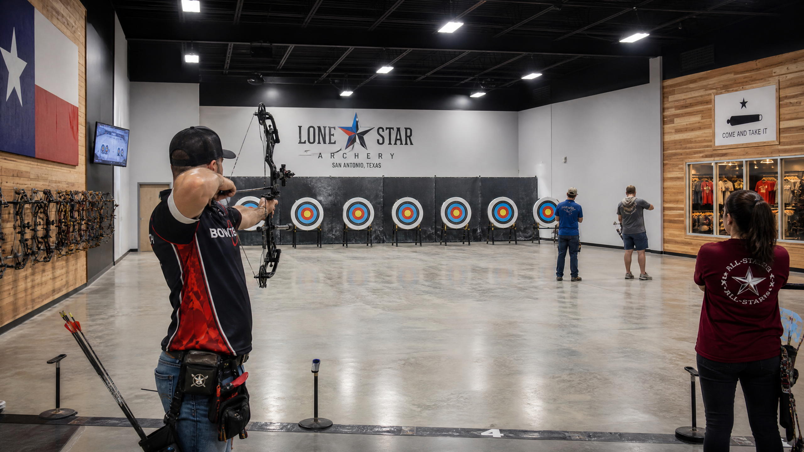 Modern indoor archery range with Lone Star branding and a compound bow